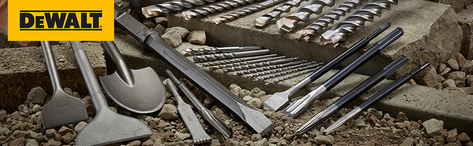 Individual drill bits and chisels lay spread out on stones and concrete parts