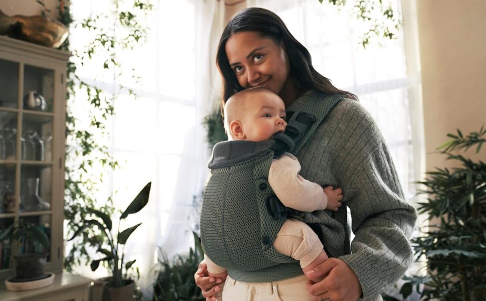 a woman holding a baby in a baby carrier.