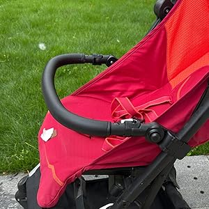Close-up of red stroller or pram parts showing black frame components and red fabric material attachment details.
