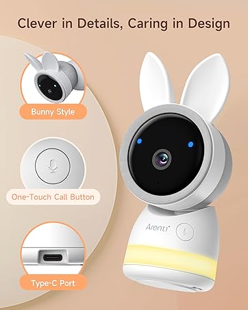 White baby monitor with bunny ear-shaped top. Circular camera lens with blue lights. Round button below. Device designed for infant monitoring and care.