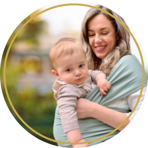 Baby carrier wrap shown in light gray fabric with a cross-body design demonstrating back-carrying position.