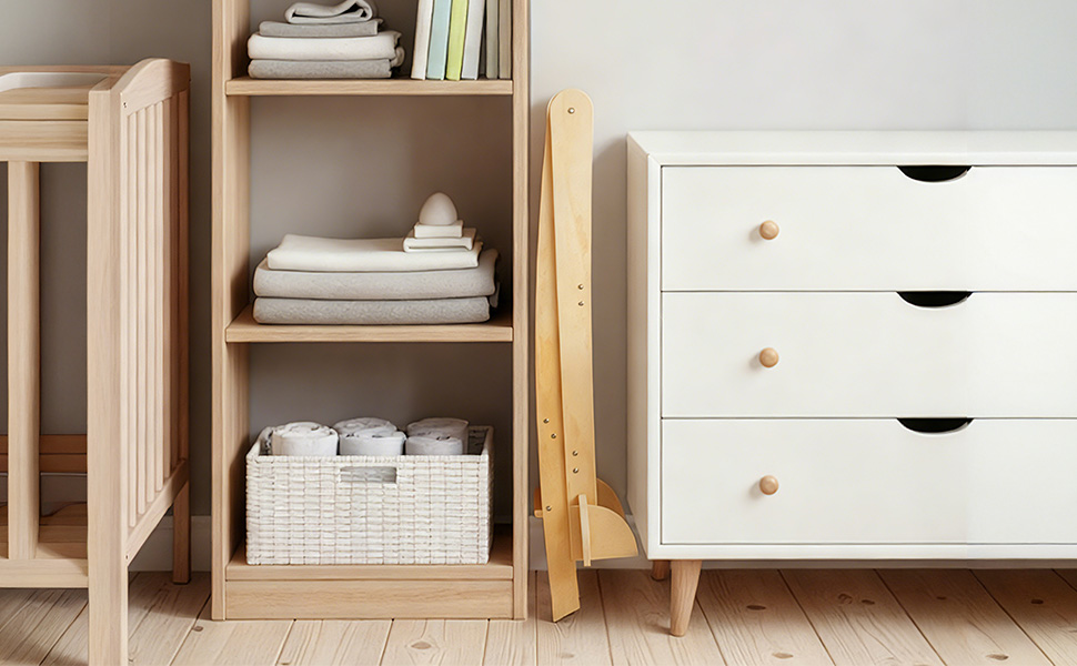 Wooden A-frame children's indoor swing set in natural finish, placed in living room with grey couch and white storage unit nearby.
