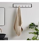 Multiple angles of light blue bath towels displayed against gray concrete wall. Towels show detailed border pattern and folded hanging presentations.