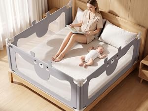 Gray fabric bed rail guard with mesh panels installed on wooden bed frame with child sleeping inside, positioned on beige carpet indoors.
