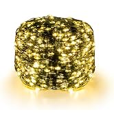 Golden star-shaped string lights and warm white lights on brick wall background. Remote control with multiple buttons displayed in foreground.